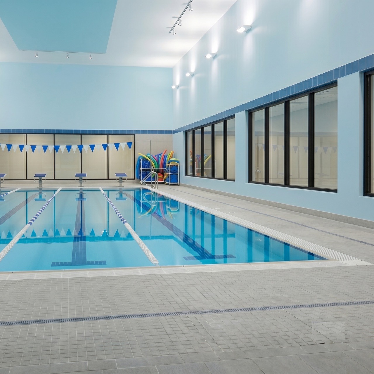 Indoor swim academy pool with lane ropes, pennant flags, and pool noodles